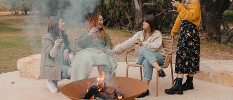 A group of people sitting around a fire pit in an outdoor setting.
