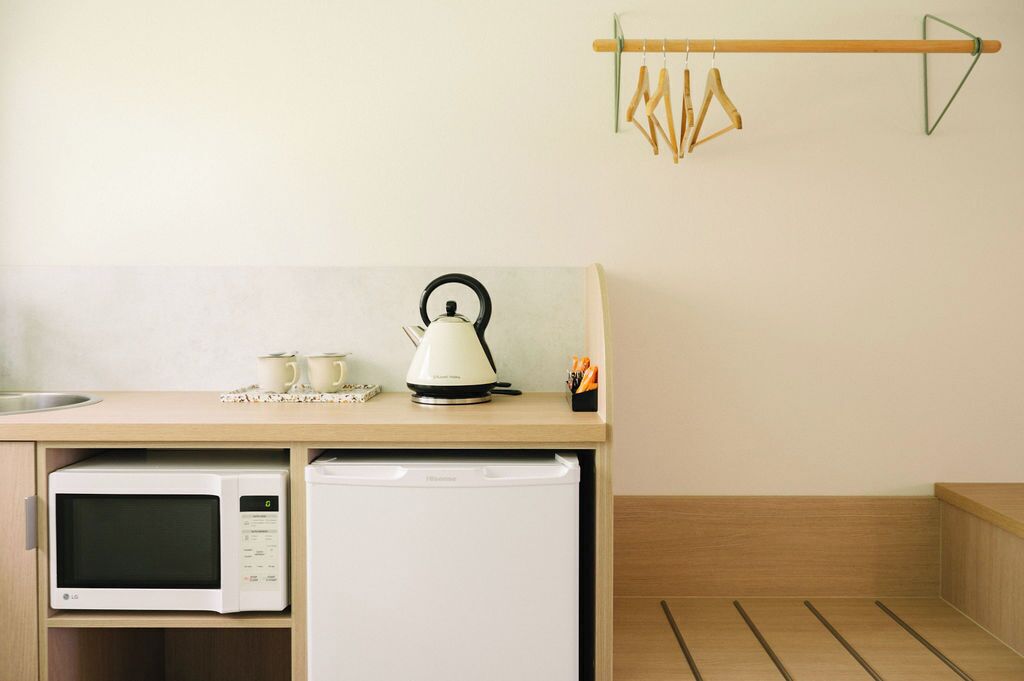 Una cocina compacta equipada con microondas, hervidor y un refrigerador pequeño.