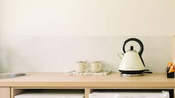 A kitchen counter with a kettle, two cups, and a tray.