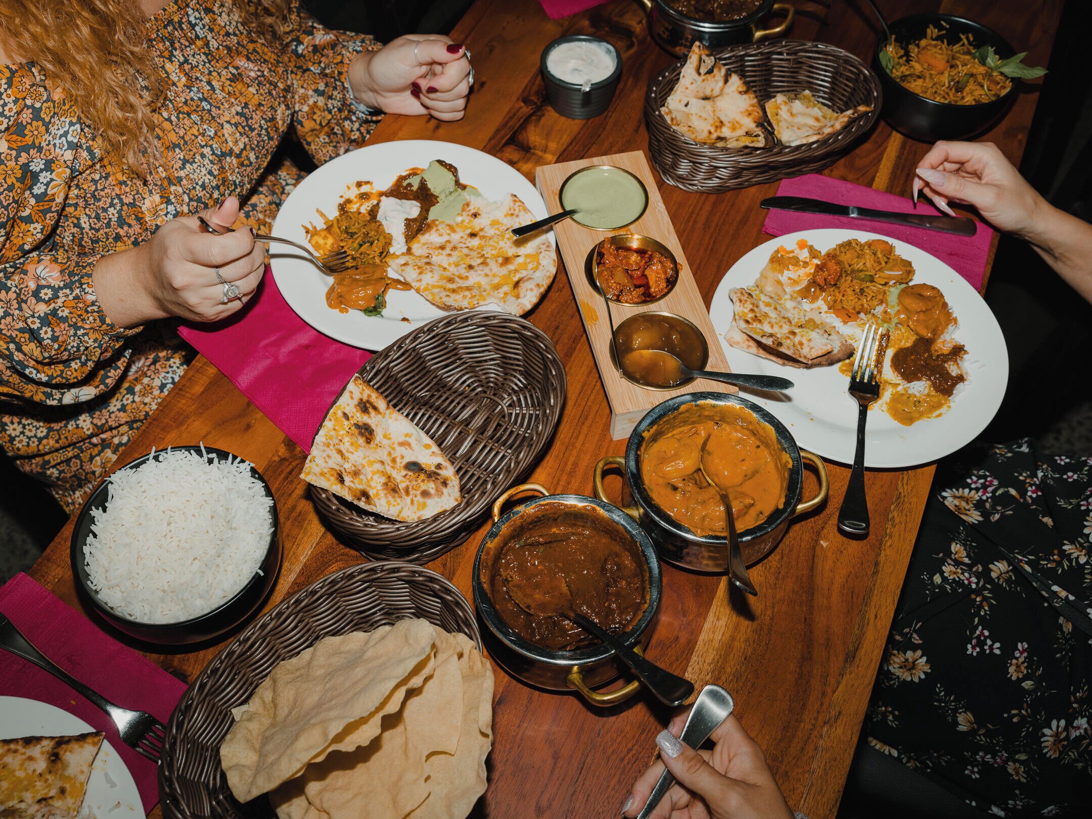 Een eettafel met diverse gerechten, zoals rijst, curry en platbrood, wat een maaltijdsetting doet vermoeden.