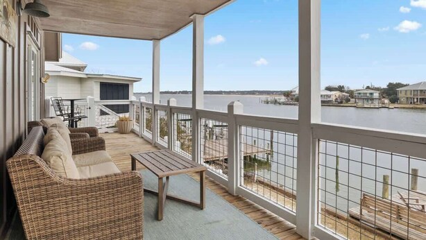 A covered outdoor area with wicker furniture and a view of a river.