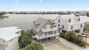 A waterfront property with a large house featuring a balcony, a smaller attached structure, and a dock.