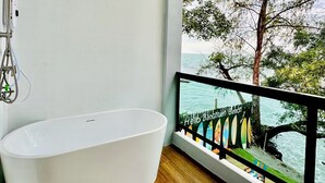 A modern bathroom with a freestanding bathtub, a shower with a handheld showerhead, and a view of a beach with a wooden pier. - Hello Banchuen Beach (Khlong Yai)