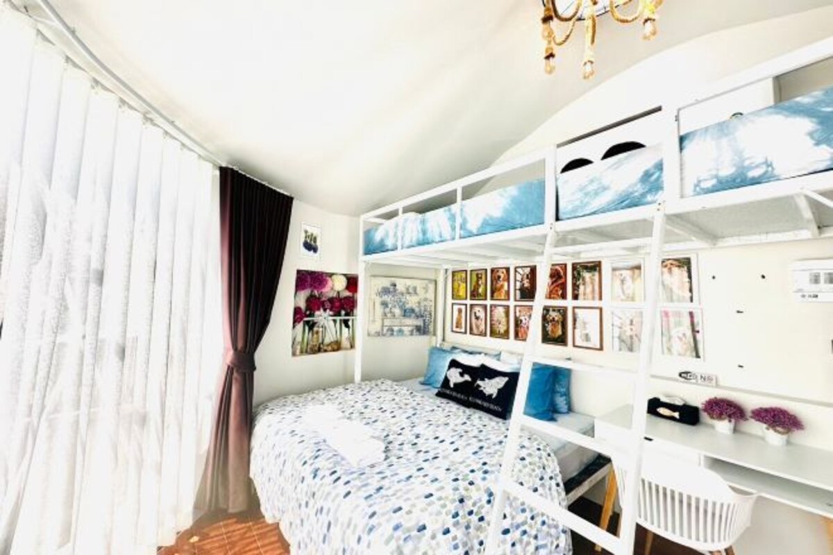 Un dormitorio con una cama, un escritorio blanco y una pared con cuadros.