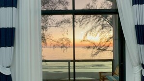 A room with a large sliding glass door leading to a balcony. The room has a wooden floor and a ceiling-mounted air conditioning unit. - Hello Banchuen Beach (Khlong Yai)