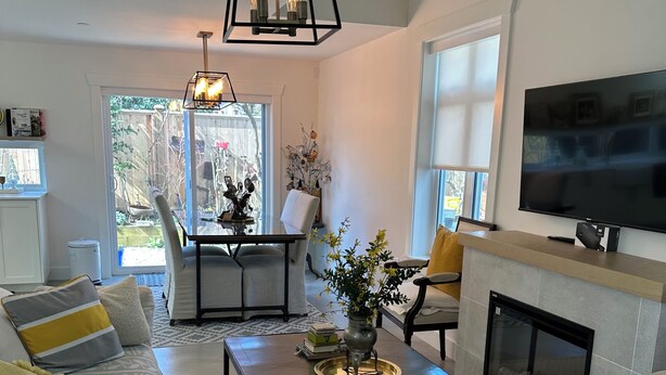 A modern living room with a fireplace, a television, and a dining area with a view of the backyard. - Charming country home in beautiful Pt Grey Village. Close to Beach, UBC, DT.  (Vancouver)