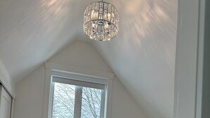 A bedroom with a bed, a window, a chandelier, and a nightstand. - Charming country home in beautiful Pt Grey Village. Close to Beach, UBC, DT.  (Vancouver)