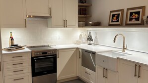 A modern kitchen with white cabinets, a stainless steel oven, a dishwasher, and a sink with a gold faucet. - Charming country home in beautiful Pt Grey Village. Close to Beach, UBC, DT.  (Vancouver)