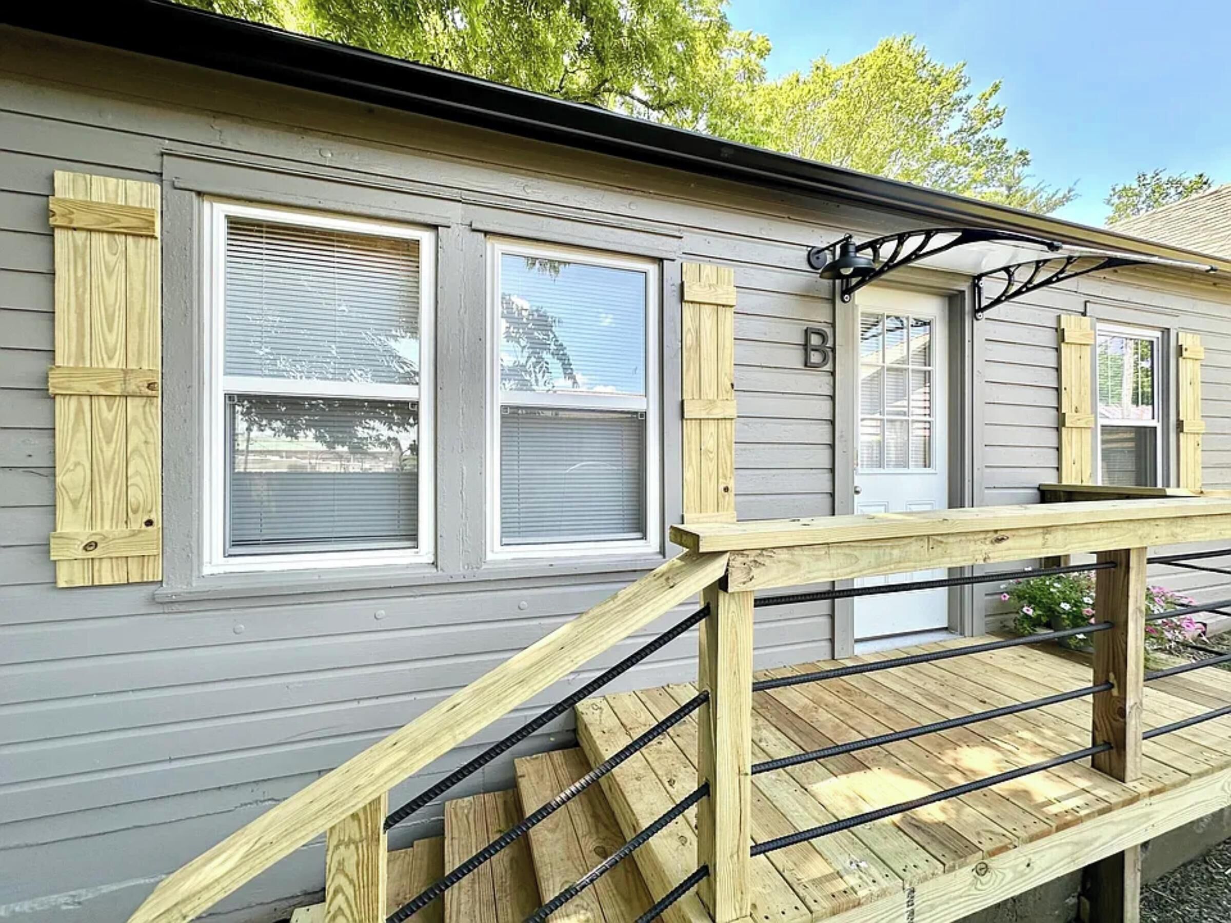 A two-story house with a wooden deck and a staircase.
