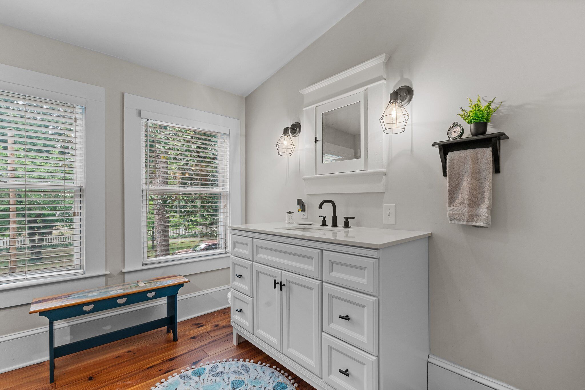 Une salle de bain avec des meubles blancs, un lavabo, un miroir et un porte-serviettes.