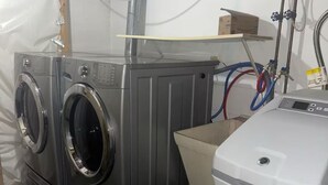 A laundry room with two stacked front-loading washing machines and a stacked dryer.