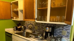 A kitchen with white cabinets, a tiled backsplash, and a stainless steel sink.