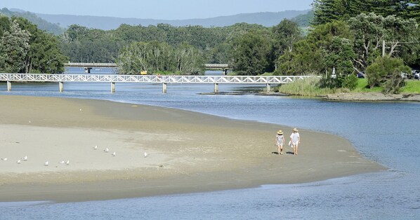 Une plage avec une jetée en bois et un pont en arrière-plan.