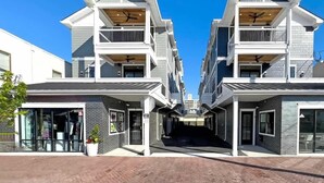 Un edificio residencial moderno con estructuras de dos pisos, balcones y un paseo central.