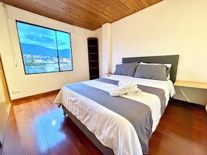 A neatly made bed with a view of a cityscape through a large window. - 2 Grand Penthouses 30 meters from Unicentro Norte Bogota (Bogotá)