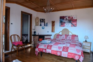 Een slaapkamer met een bed, een stoel, een open haard en een muur met kunstwerken.