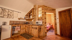 Une cuisine rustique avec des meubles en bois, un four à micro-ondes et un petit réfrigérateur.
