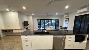A modern kitchen with a central island, white cabinetry, and a built-in dishwasher. - 1BR (sleeps 3) - private, modern granny flat with large shaded pool (Parap)