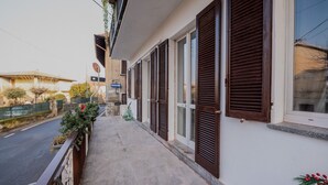 Un immeuble résidentiel doté d’un balcon, donnant sur la rue, et sur lequel est apposée une enseigne indiquant une direction.