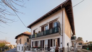 Un immeuble de deux étages doté d’un balcon, donnant sur la rue, et avec un ciel dégagé.