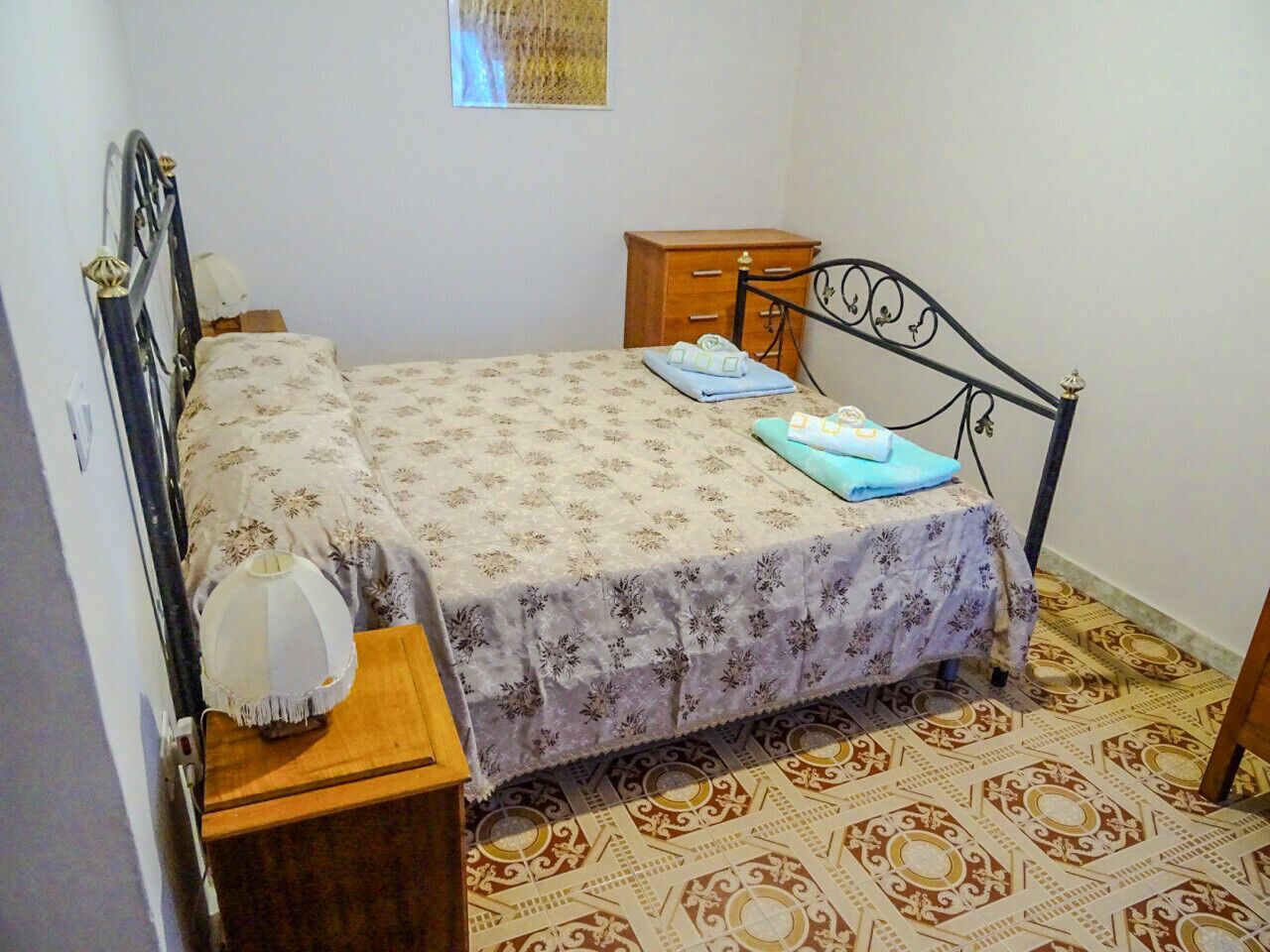 Une chambre à coucher comprenant un lit, une table de chevet, une commode et un revêtement de sol à motifs.