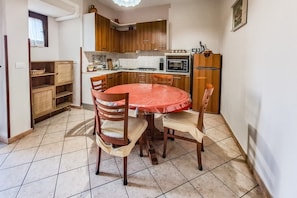 A compact kitchen with wooden cabinets, a gas stove, a microwave, and a refrigerator.