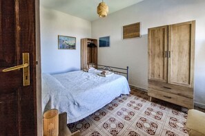 Een slaapkamer met een bed, een houten kledingkast en een vloer met een patroon.