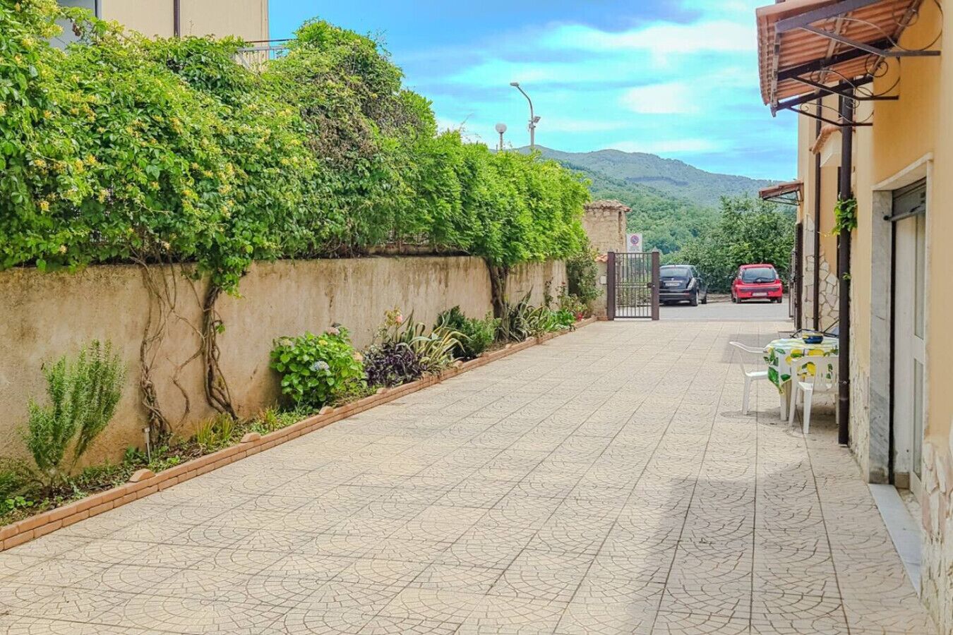 Un camí pavimentat amb una porta, una taula amb caires, i un cotxe estacionat a la distància.