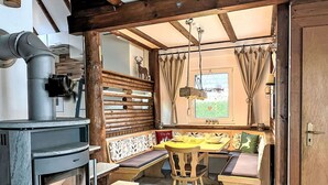 A cozy kitchen with a wood-burning stove, a bench seating area, and a window with curtains.