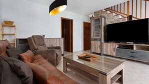 Una sala de estar moderna con sofá, mesa de centro, televisor y escalera de madera.
