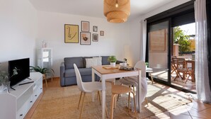 A modern living room with a sofa, dining table, chairs, and a TV.