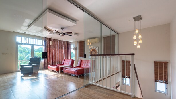 Amplia sala de estar con un gran ventanal, ventilador de techo y una escalera.