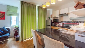 Una cocina moderna con una isla central, un área de comedor con mesa y sillas, y una sala de estar con sofá y una mesita auxiliar.