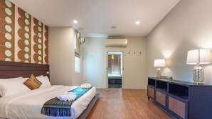 Una habitación de hotel con una cama, una mesita de consola con lámparas y un equipo de aire acondicionado.