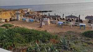 Un espace aménagé au bord de la plage, avec un bâtiment, des tables, des chaises et des parasols.