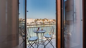 Un balcon avec une table et des chaises, donnant sur une marina où sont amarrés des bateaux.