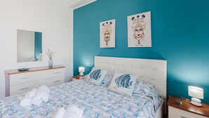 Een slaapkamer met een bed, twee nachtkastjes, een spiegel en kunst aan de muur.