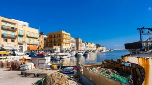 Un port de plaisance situé au bord de l’eau, avec des bateaux, un quai et des bâtiments le long de la rive.