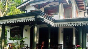 A traditional house with a covered porch, wooden furniture, and potted plants. - Villa Gajeru Walawwa by W Lanka (Balapitiya)