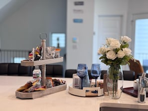 Un vestíbulo de hotel con una mesa de buffet, un jarrón con flores blancas y una zona de estar al fondo.