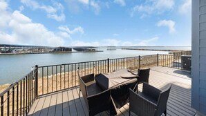 Una terrazza con mobili in vimini che si affaccia su uno specchio d'acqua e un ponte in lontananza.