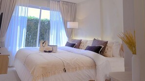 A modern bedroom with a large bed, a bedside table, a lamp, and a view of greenery outside. - Amazing new 1-bedroom apartment, fabulous Lamai Beach,  swimming pool, fitness (Koh Samui)