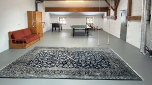 Um quarto amplo com um tapete grande estampado, um sofá, uma mesa e uma mesa de pingue-pongue.