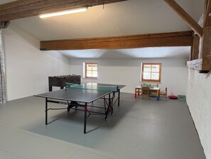 A room with a ping pong table, two windows, a foosball table, and a small table with chairs. - No.1 - Holiday apartment Winklmoos (Reit im Winkl)