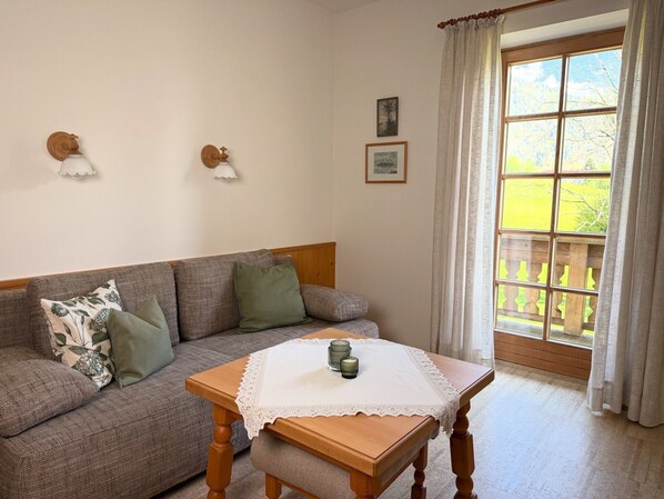 Une pièce chaleureuse avec une table en bois, un canapé et une fenêtre avec des rideaux.