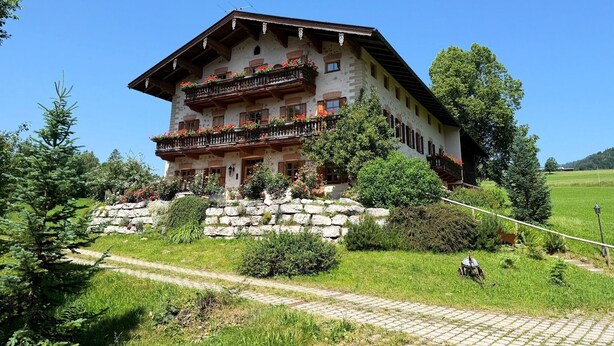 Ein mehrgeschossiges Gebäude mit Balkonen, umgeben von viel Grün und blauem Himmel.