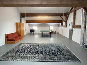 Une pièce spacieuse avec un grand tapis à motifs, un canapé, une table de baby-foot et une table de ping-pong.