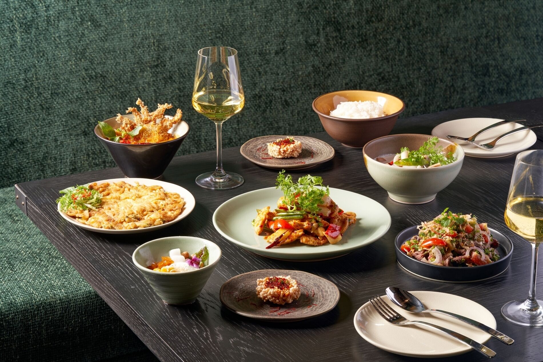 Variedad de platos sobre una mesa con copas de vino y cubiertos.