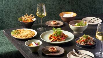 Variedad de platos sobre una mesa con copas de vino y cubiertos.