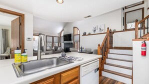 A modern kitchen with a large island, stainless steel sink, wooden cabinets, and a built-in dishwasher. - 2 Bedroom, beautiful end unit (Galena)